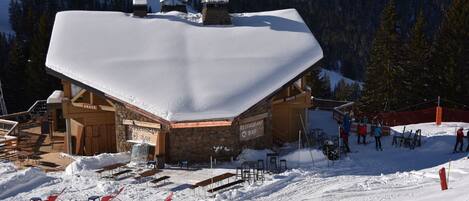 A snow-covered building with a restaurant bar and outdoor seating area.