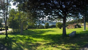 Uma área de parque com gramado, árvores e um banco de pedra.