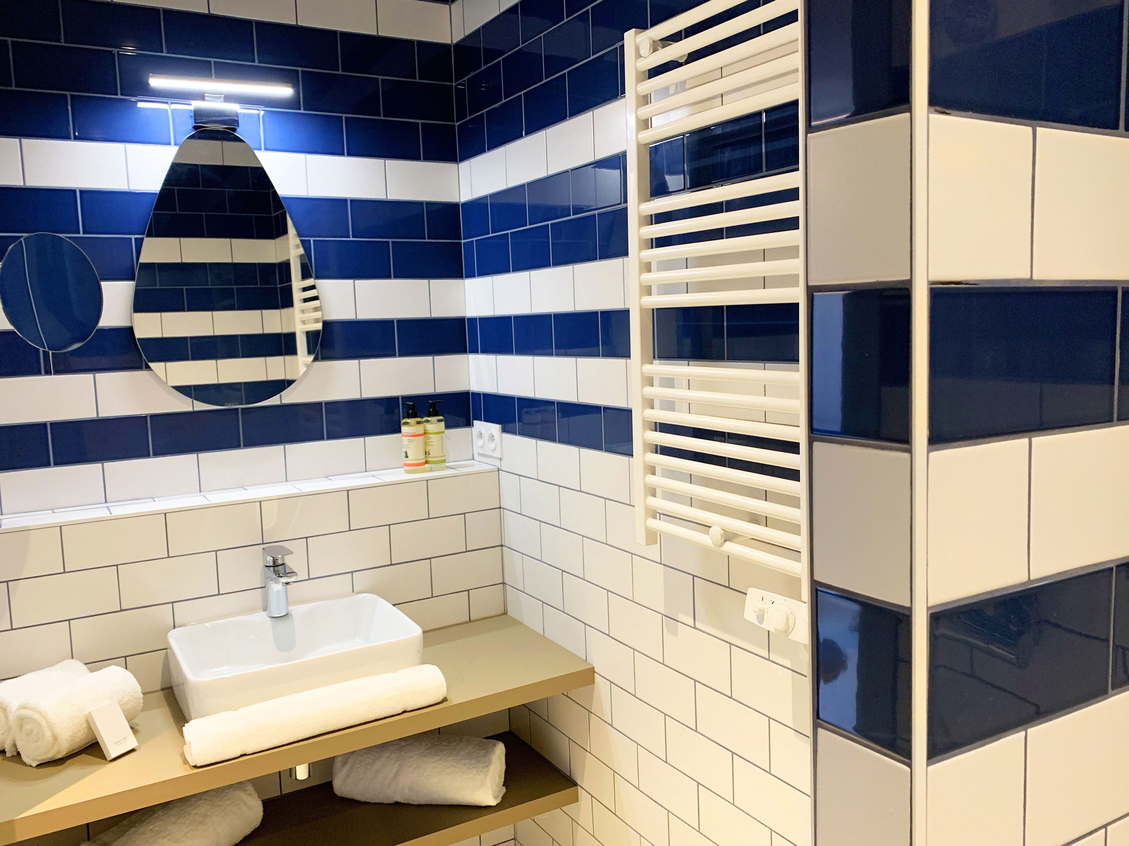 A bathroom with a white sink, a mirror, and a towel rack.