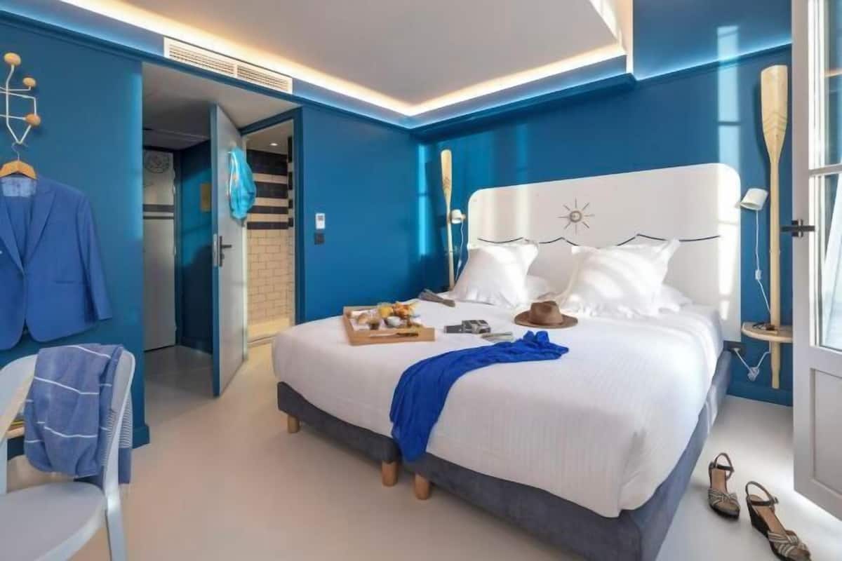 Een moderne hotelkamer met een groot bed, een zithoek met een stoel, een kledingkast en een zichtbare badkamer.