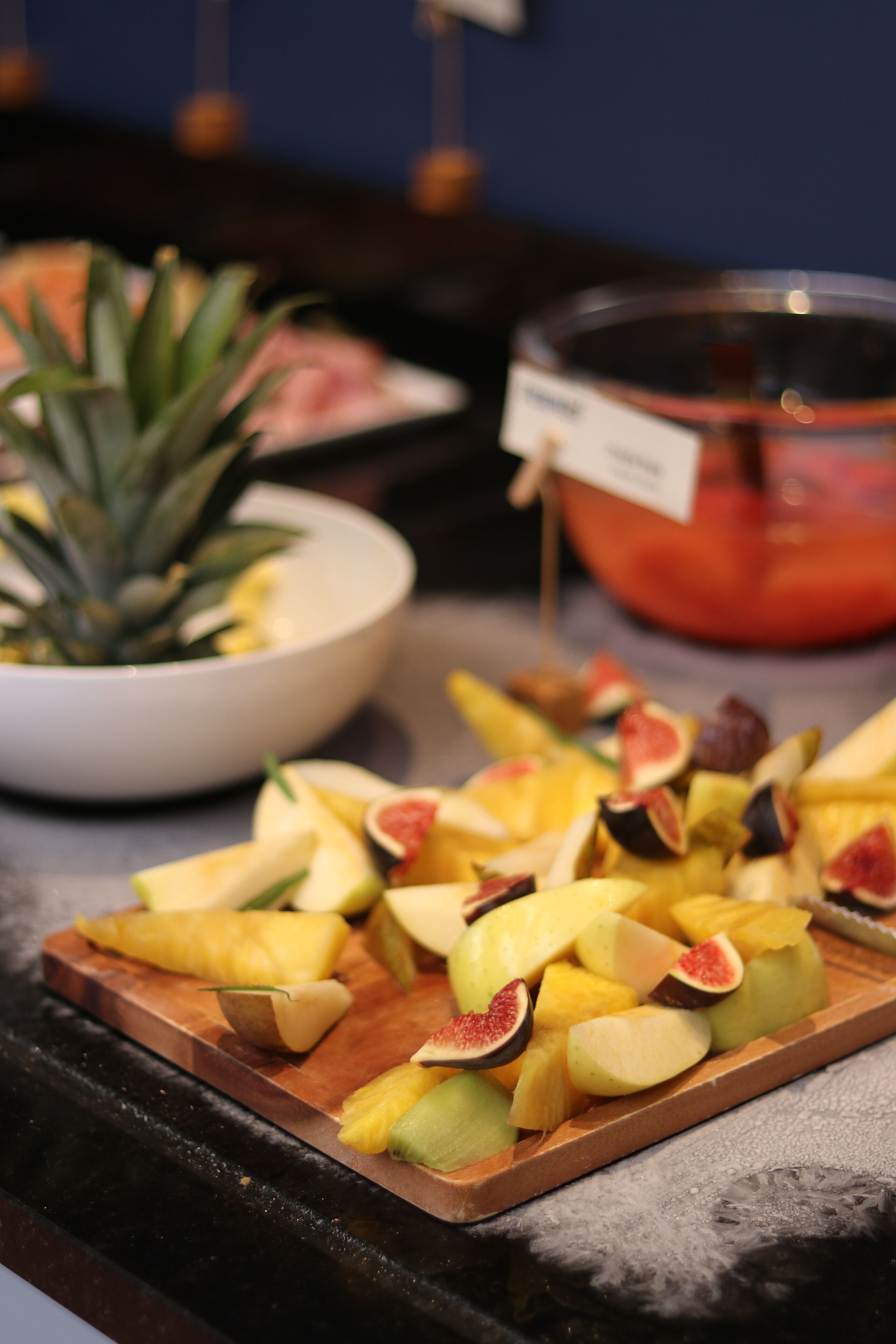 Una bandeja de frutas con piña y melón sobre una tabla de madera.
