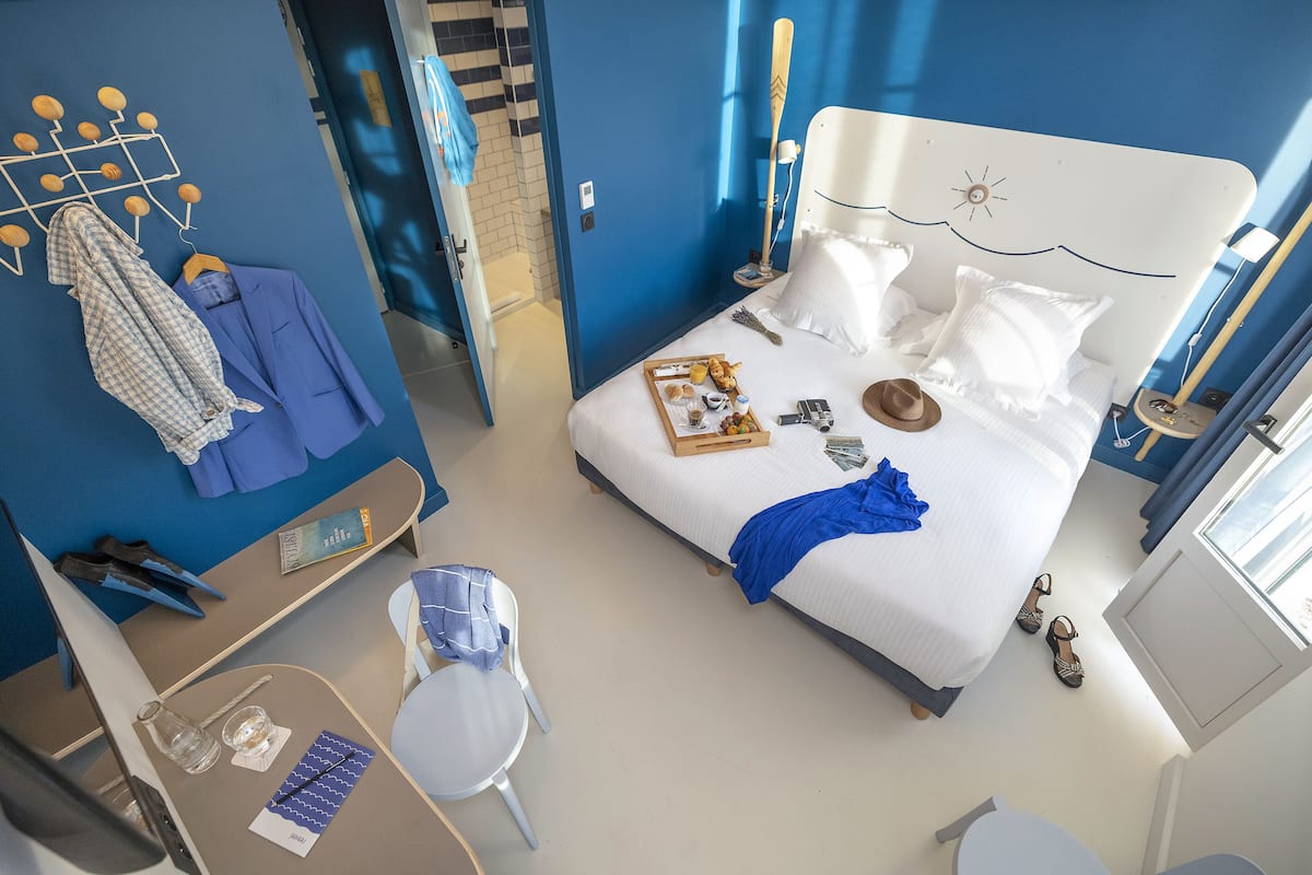 Een hotelkamer met een bed, een bureau, een stoel en een badkamer die door een open deur zichtbaar is.