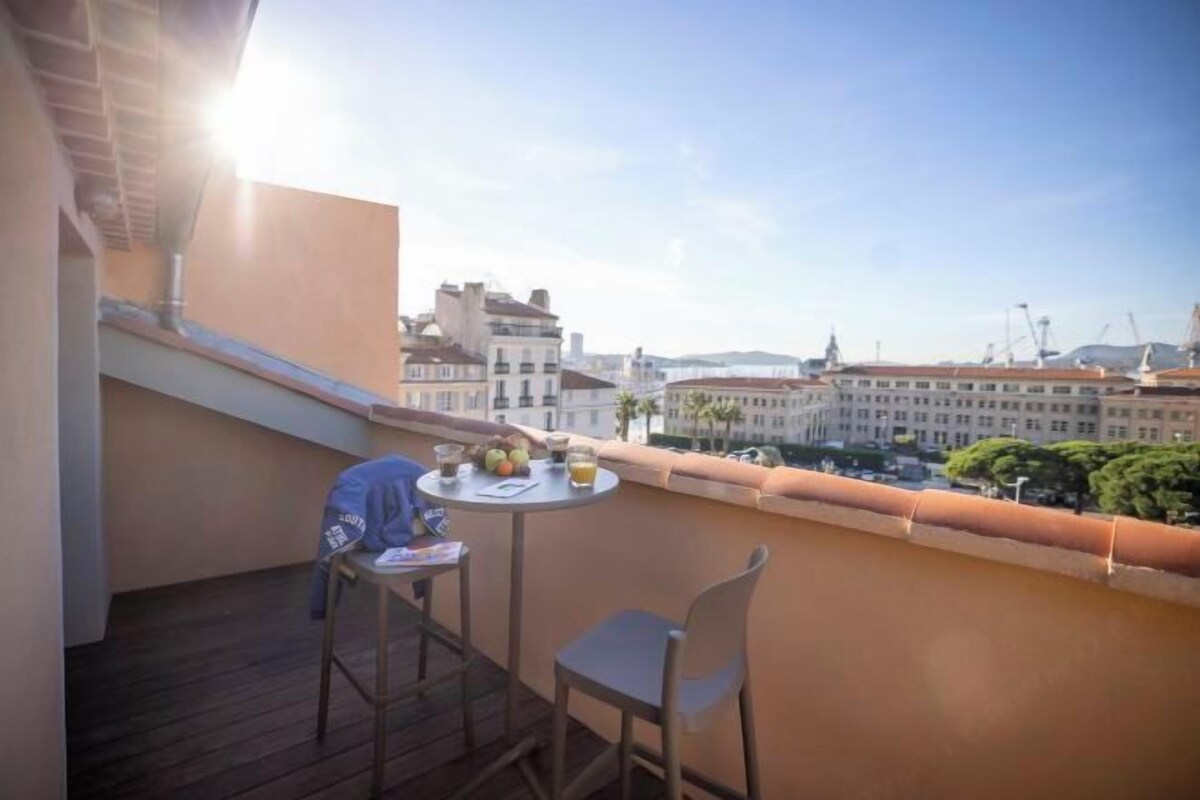 Een balkon met een tafel, stoelen en uitzicht op gebouwen.