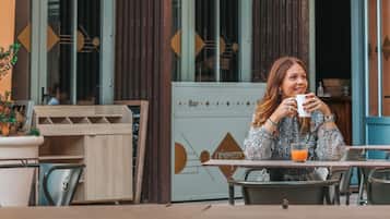 Una cafetería llamada 'l'équerre' con terraza y fachada de madera rústica.