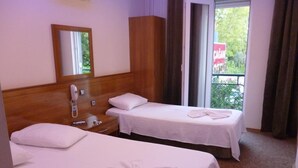 Habitación de hotel con dos camas, cabecero de madera, teléfono junto a la cama y ventana con vistas a zonas verdes.
