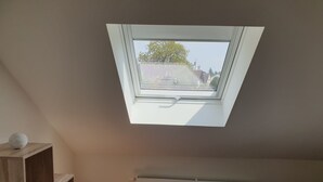 A bedroom with a sloped ceiling, a skylight, a radiator, and a wooden shelf with a globe. - Apartment cozy in the DG (Alzey)