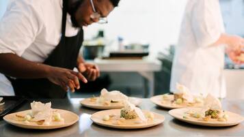 Chefs preparing dishes on plates in a kitchen setting.