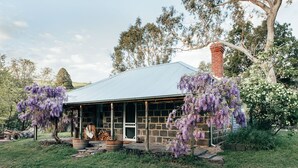 A stone building with a metal roof, surrounded by trees and grass. - ELLERSLIE COTTAGE - FOR LOVERS AND DREAMERS (Glenhope)