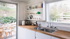 A kitchen with white cabinets, a wooden countertop, and a window with blinds. - ELLERSLIE COTTAGE - FOR LOVERS AND DREAMERS (Glenhope)