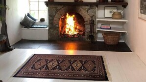 A cozy room with a stone fireplace, a bench, and a rug. - ELLERSLIE COTTAGE - FOR LOVERS AND DREAMERS (Glenhope)