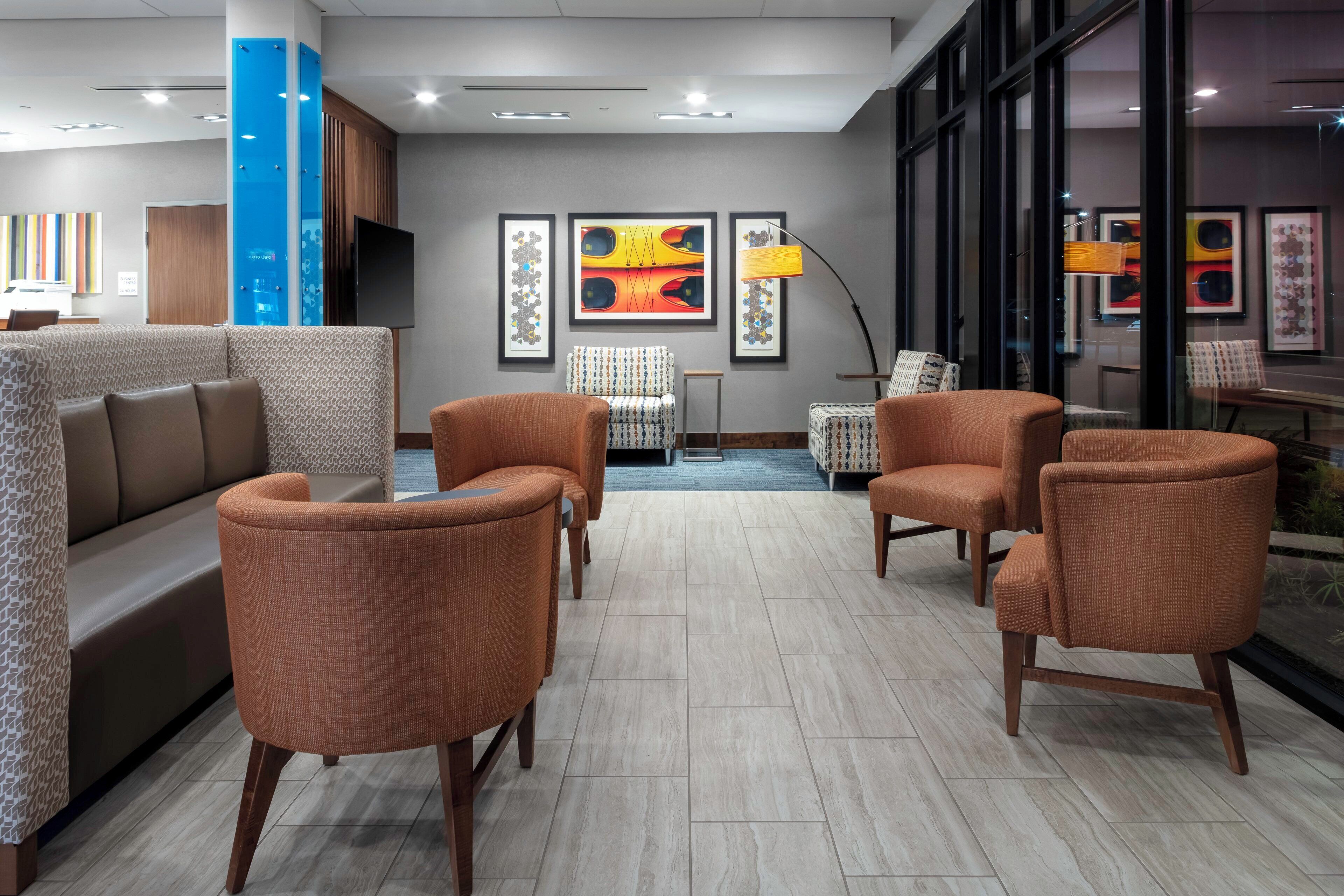 Un espacio lounge moderno con sofás y sillones, un pilar azul y obras de arte en las paredes.