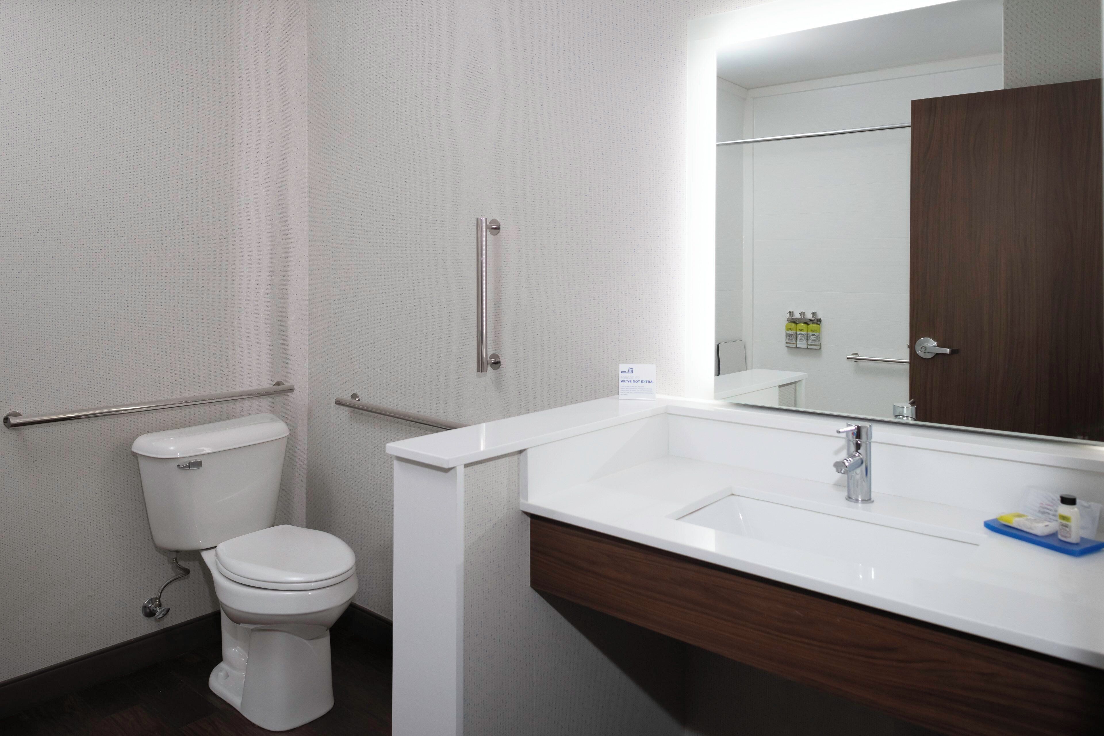A bathroom with a white toilet, a sink with a mirror, and a wooden cabinet.