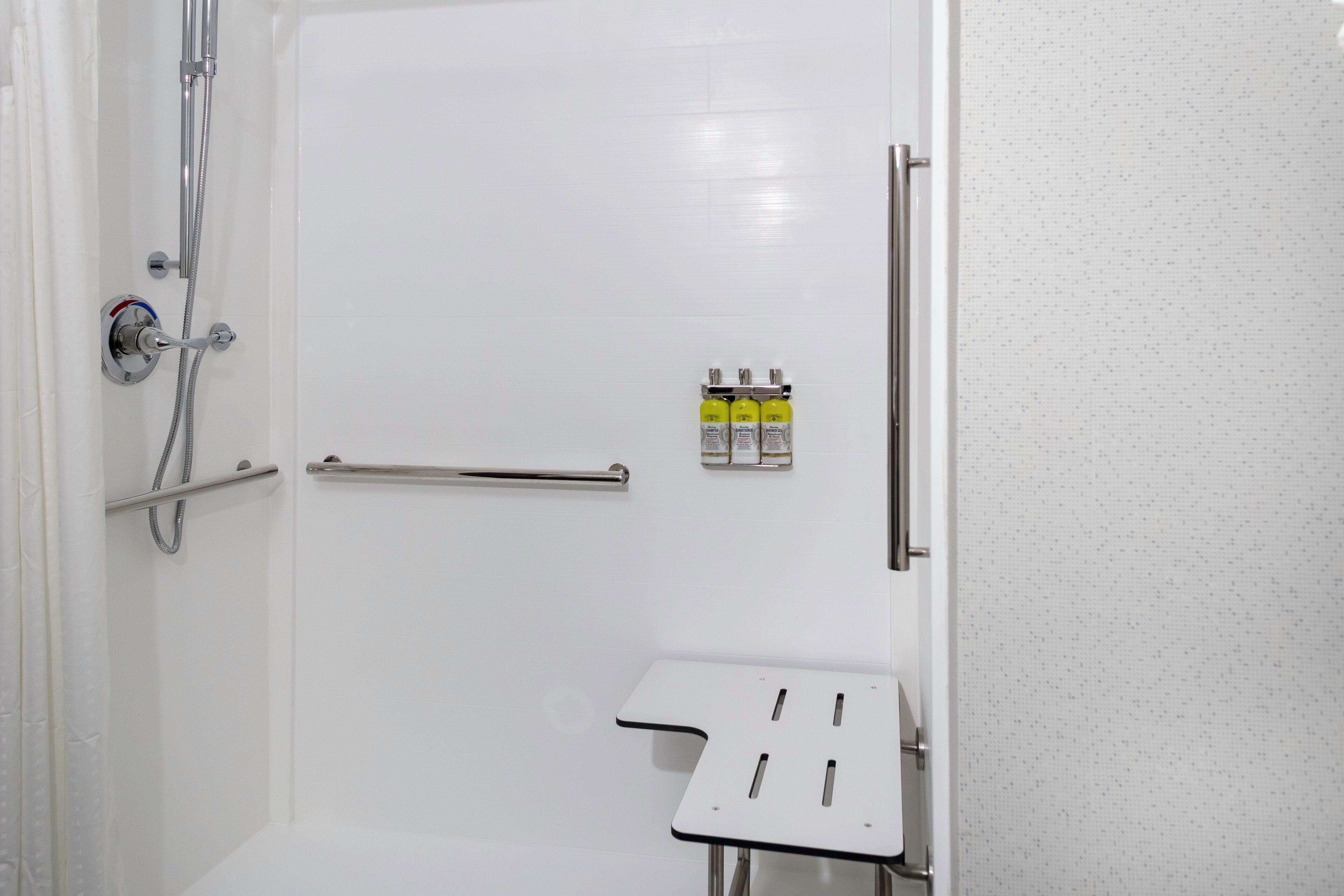 Casa de banho com chuveiro, porta-toalhas e um pequeno armário com artigos de higiene pessoal.