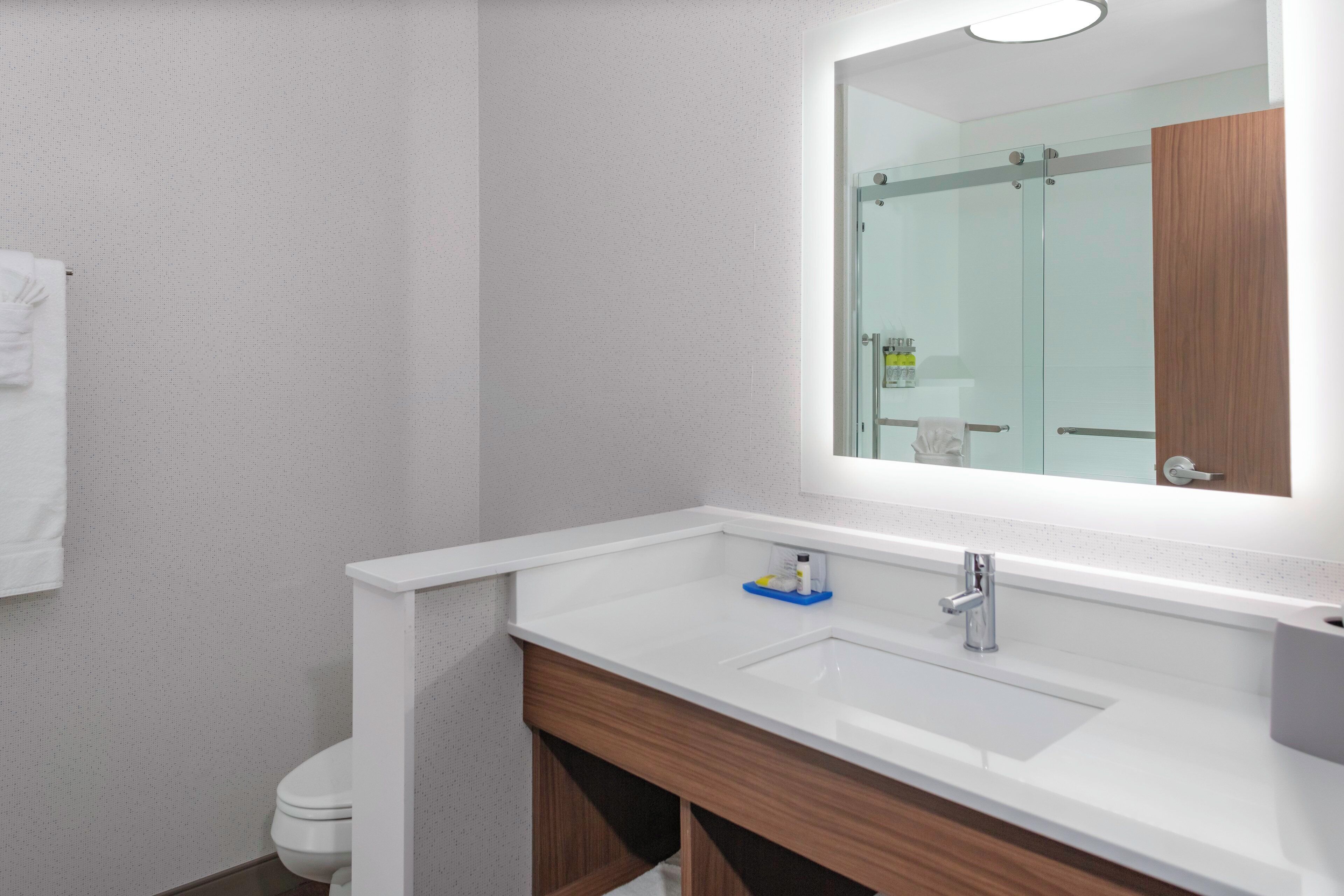 A bathroom with a white sink, a mirror, and a toilet.