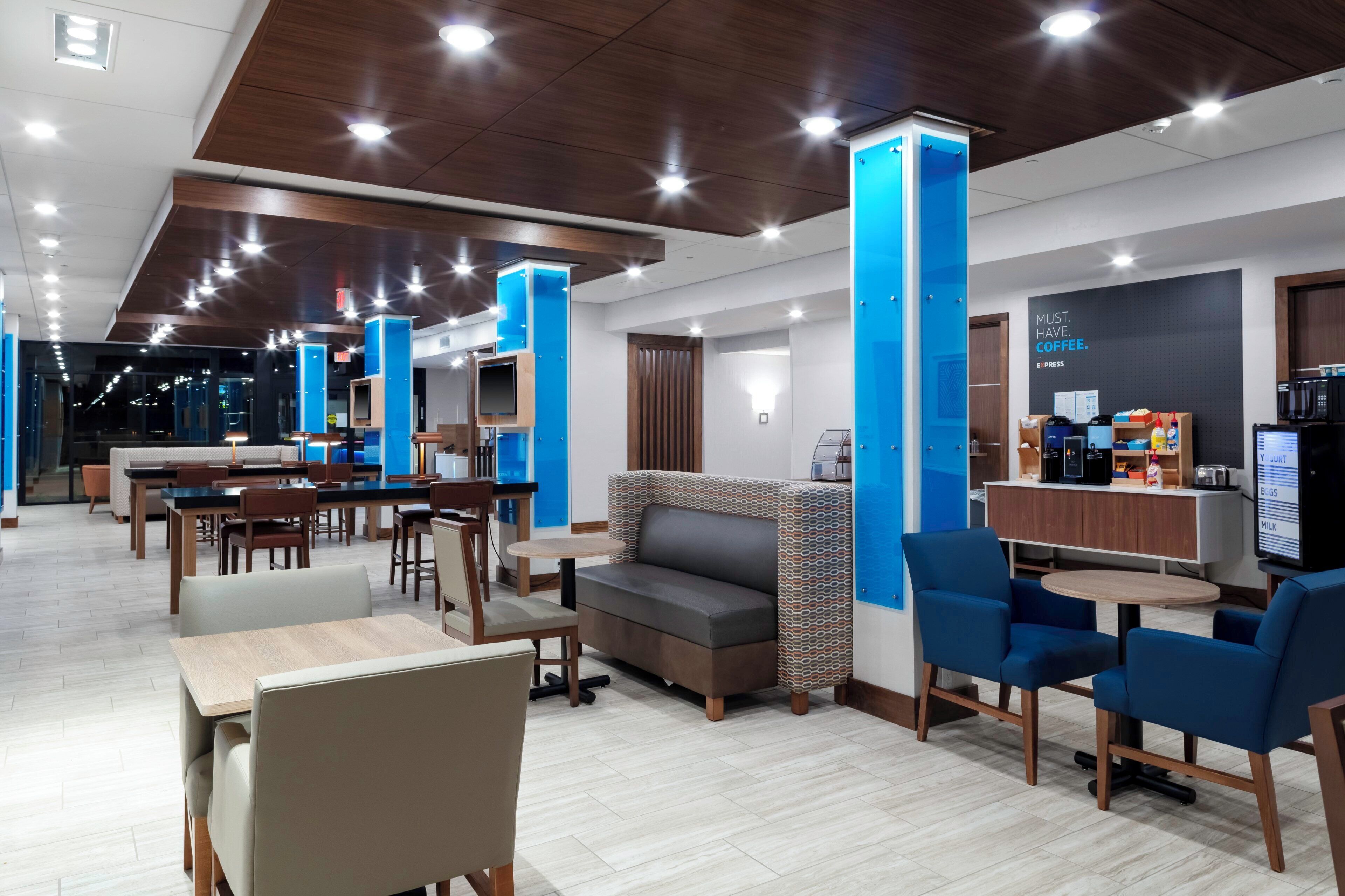 A modern hotel lobby with a seating area, a coffee station, and a reception desk.
