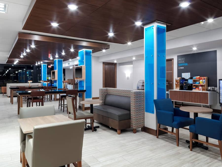 A modern hotel lobby with a seating area, a coffee station, and a reception desk.