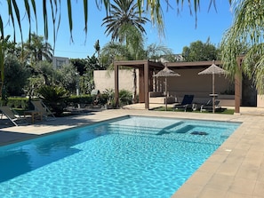 حمّام سباحة خارجي، مظلات على حمّام السباحة، مقاعد للتشمس