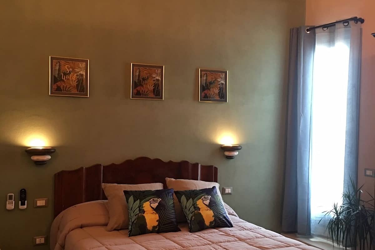 A bedroom with a large bed, a wooden headboard, and three wall-mounted lamps.