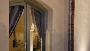 A glass door entrance to a room with a stone floor, a bamboo column, and a potted plant visible inside. - Signorino Suites&Pool (Marsala)
