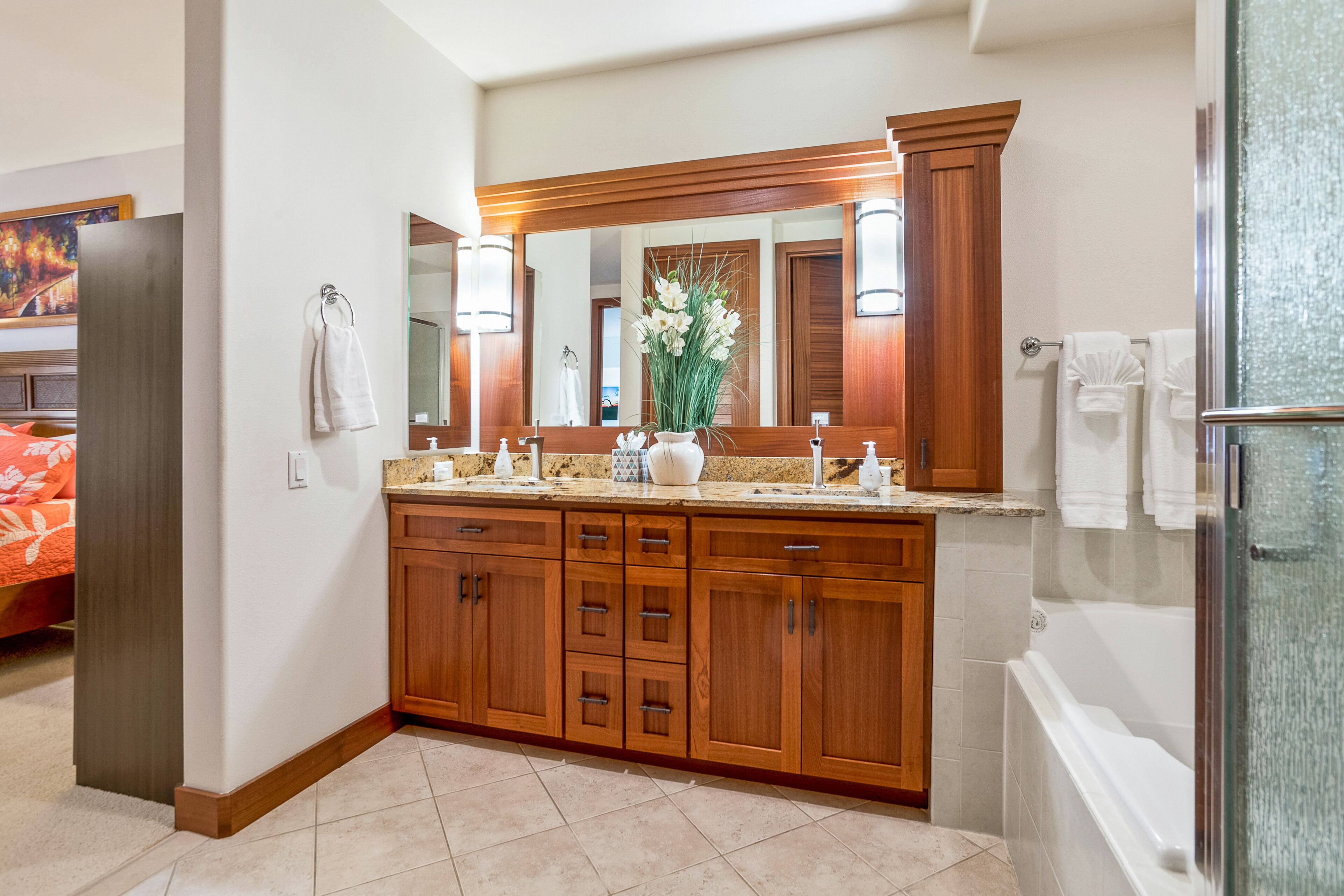 A modern bathroom with a wooden vanity, a large mirror, and a glass shower enclosure.
