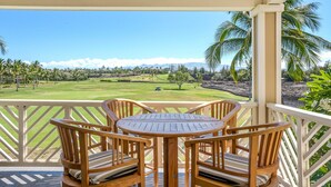 Una terraza de madera con mesa y sillas que da a un campo de golf.