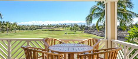 A wooden deck with a table and chairs overlooking a golf course.