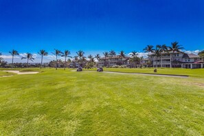 Un campo de golf con un club de campo y varios edificios al fondo.
