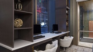 A modern office space with a desk, two chairs, and decorative items on shelves. - Hyatt Place Tulsa Downtown (Tulsa)