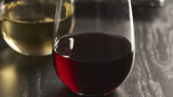 Two wine glasses, one with white wine and the other with red wine, on a wooden table.