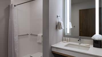 Ein modernes Badezimmer mit Dusche, Waschbecken mit Spiegel und Handtuchhalter.