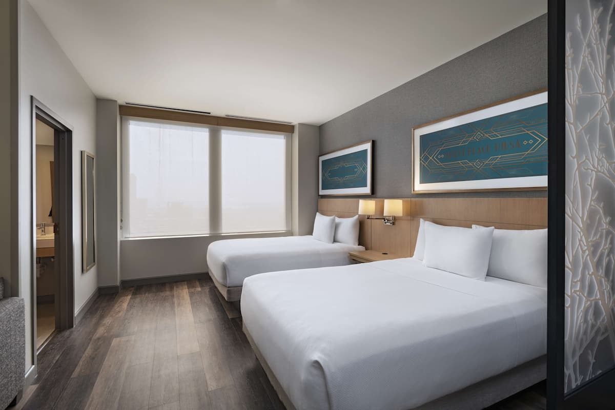 Ein Hotelzimmer mit zwei Betten, einem großen Fenster und Bildern an den Wänden.