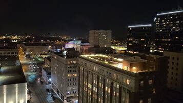 A nighttime cityscape with illuminated buildings, including a prominent hotel with a classic architectural style.