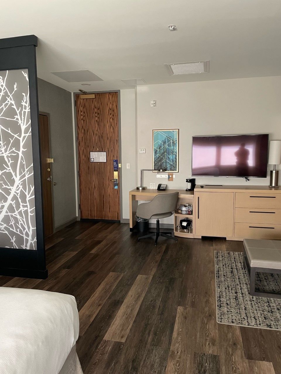 Una habitación de hotel con una cama, un escritorio con silla, televisión y armario.