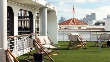 A rooftop terrace with outdoor seating and a city skyline view.