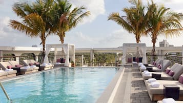 Relax by the rooftop pool with city views, surrounded by lounge chairs and palm trees.