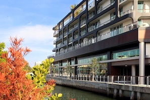 A multi-story building with balconies, a bridge, and water in the foreground. - Kimpton Hotel Palomar South Beach by IHG (Miami Beach)