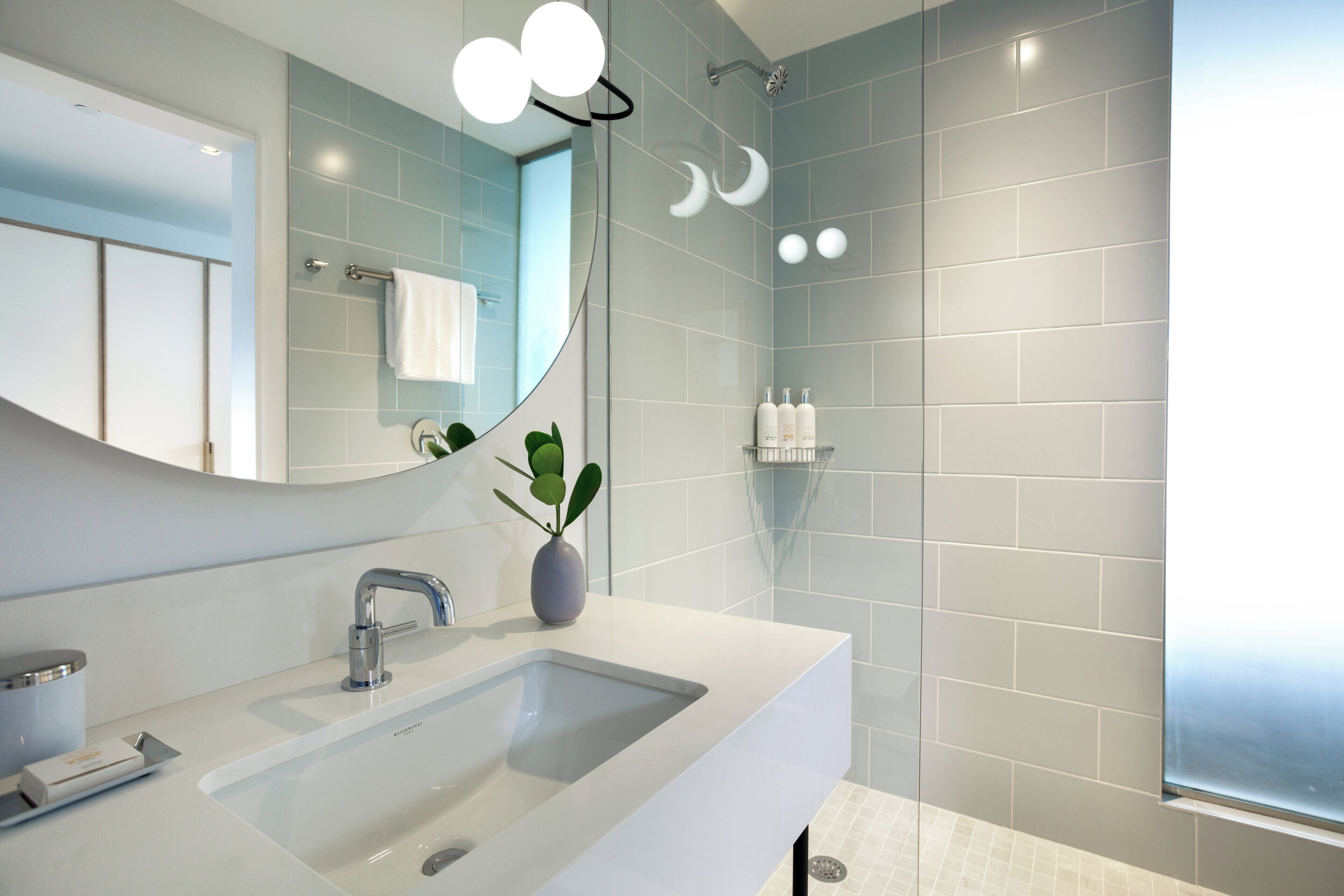 A modern bathroom with a large mirror, a sink, and a shower area.