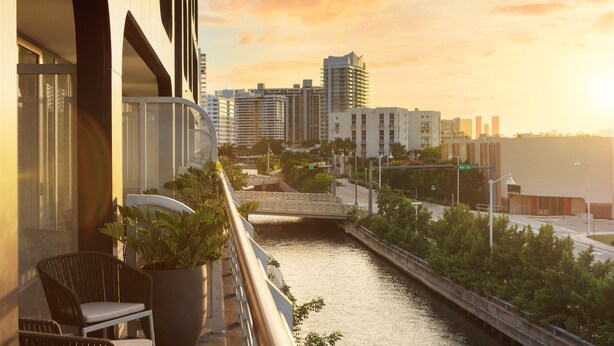 Un balcón con vistas a un río, un puente y edificios altos al fondo.