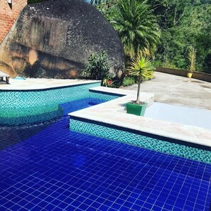 Una piscina al aire libre, sillones reclinables de piscina