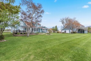 A residential area with multiple houses, well-maintained lawns, and trees. - Deck + Fire Pit: Waterfront Lake Michigan Escape (Algoma)
