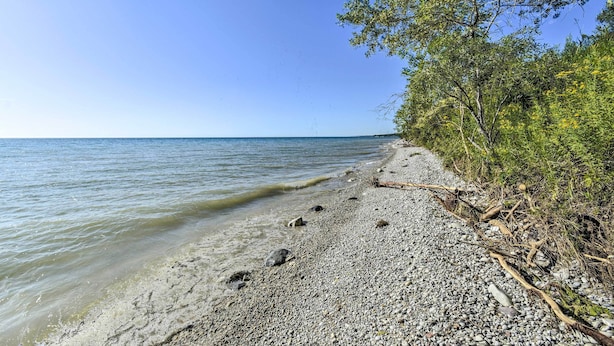 A pebbled beach with clear water and trees on the right. - Deck + Fire Pit: Waterfront Lake Michigan Escape (Algoma)