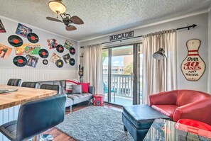 Un salon chaleureux avec une table à manger en bois, des sièges confortables, un ventilateur de plafond et un mur décoré de disques vinyle.