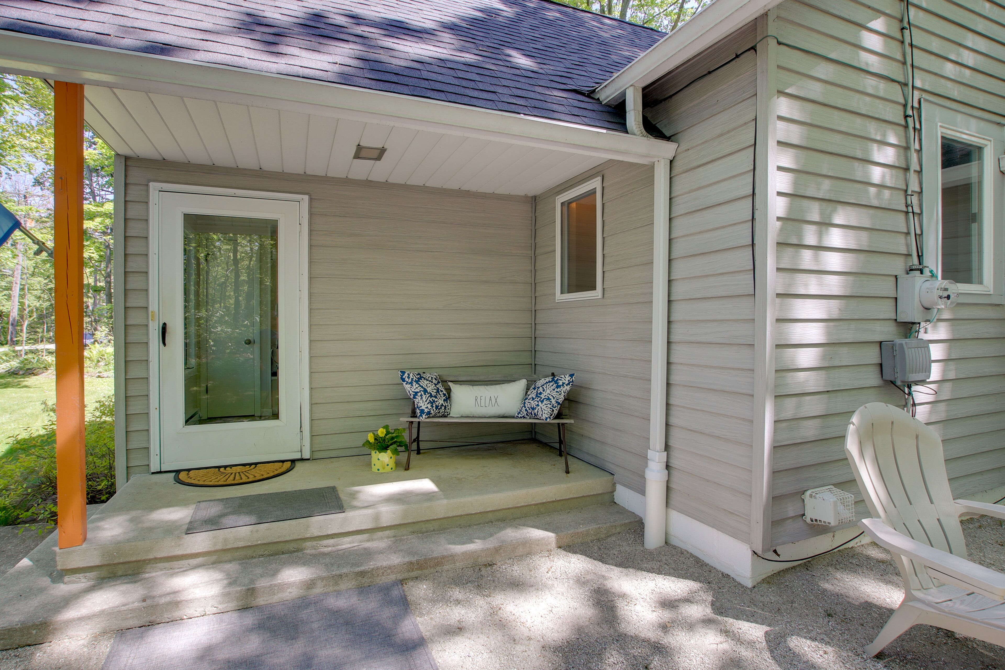 A porch with a bench, a door, and a chair.