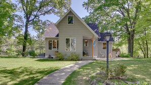 A single-story house with a front porch, a pathway leading to the entrance, and a small garden area with plants and a rock feature. - Updated Home w/ Deck: 2 Mi to Sister Bay Beach! (Sister Bay)