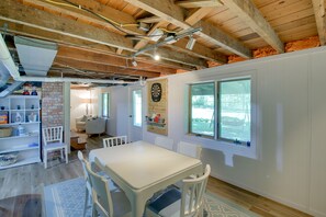 A dining area with a white table and chairs, a brick wall, and a dartboard. - Updated Home w/ Deck: 2 Mi to Sister Bay Beach! (Sister Bay)