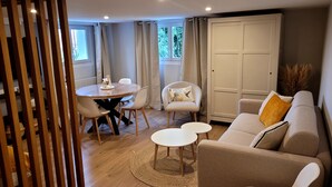 A modern living room with a round dining table, two white chairs, a beige sofa with a yellow pillow, and a large white wardrobe.