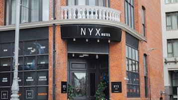 A NYX Hotel with a black facade, large windows, and a black entrance.