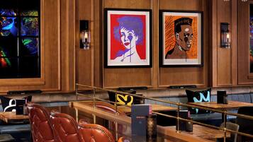 Zona de bar con taburetes de cuero, obras de arte enmarcadas en la pared y un diseño moderno del techo.