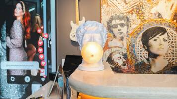 Una habitación con una lámpara decorativa, una guitarra y un cartel con el retrato de una mujer.