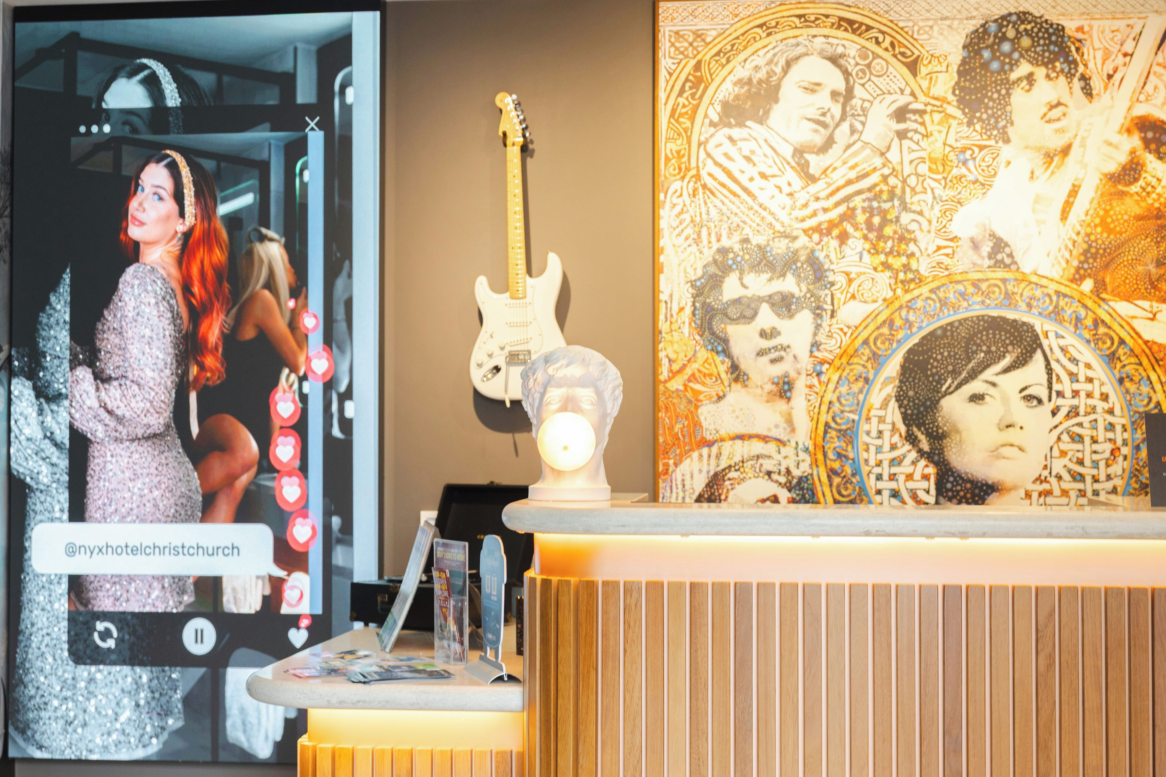 Un mostrador de recepción de hotel con un espejo, una guitarra y un adorno de pared.